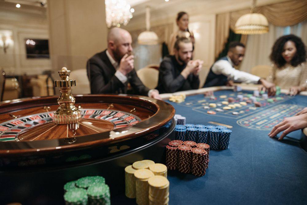Meja roulette dengan dealer dan pemain di kasino